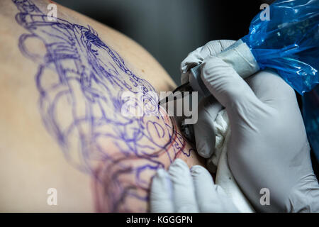 A Tattoo Artist at Work,A tattoo artist inks a designed onto the back of a local girl in his studio in Leeds. Stock Photo