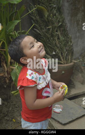 Young Nepalese girl smiling, looking up during a Jatra festival in Panauti, Nepal. Hindu festival. She has a black strip on forehead. Stock Photo