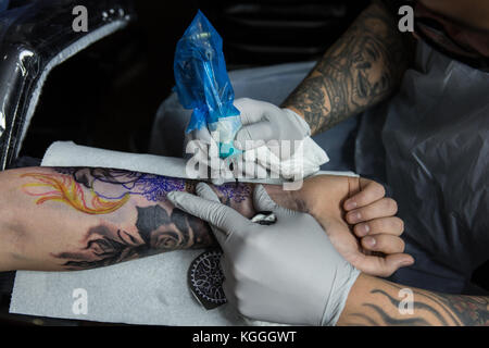 A Tattoo Artist at Work,A tattoo artist inks a designed onto the back of a local girl in his studio in Leeds. Stock Photo