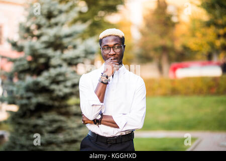 Young handsome afro american man with blonde hair walking in the sunny city streets. Stock Photo