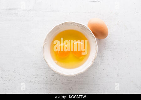 Top of view eggs in bowl on white concrete board. Stock Photo