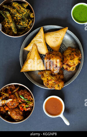 Selection of Indian dishes: samosas, onion bhaji, manchurian balls and okra Stock Photo