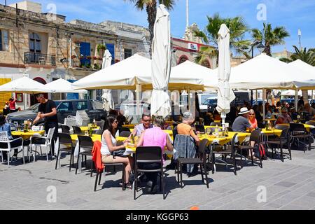 Tourists relaxing at a pavement cafes along the waterfront, Marsaxlokk, Malta, Europe. Stock Photo