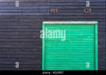 green wooden door on a black clapboard wall. Stock Photo