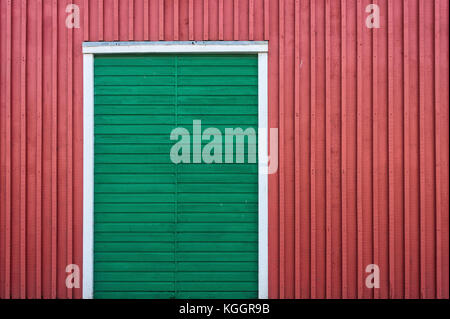 Green wooden door on a red wooden wall Stock Photo