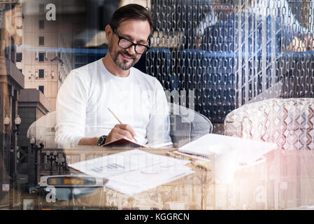 Handsome man in eyeglasses writing in his notebook Stock Photo