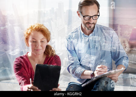 Pleasant woman taking a selfie while man working Stock Photo