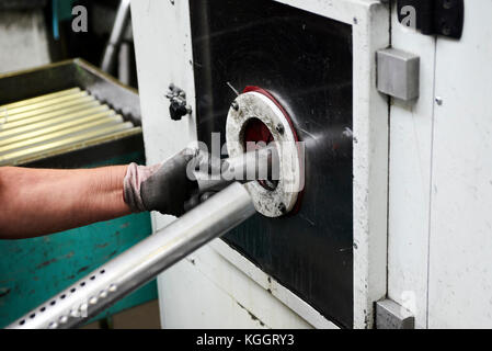 Inside a factory, industrial worker in action on metal machine Stock Photo