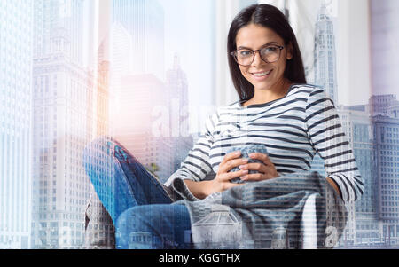 Happy young woman sitting and smiling cheerfully Stock Photo