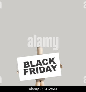 Wooden Mannequin holds sign with text Black Friday for Discount day on market on gray background Stock Photo