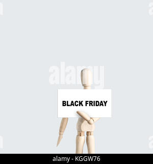 Wooden Mannequin holds board with text Black Friday for Discount day on market on light gray background Stock Photo