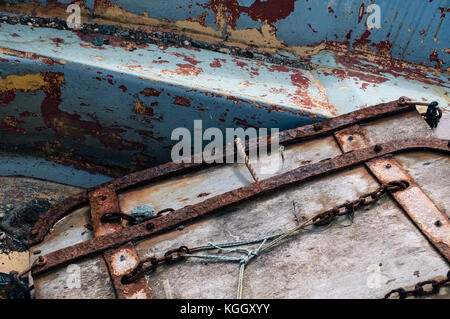 Close up photograph of the rust and worn, peeling paint on two old discarded boats on the quay side. Stock Photo