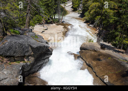 A small rainbow over the Merced River in Yosemite National Park with its many cascades as it winds its way through the park. Stock Photo