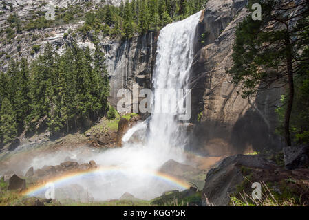 Vernal falls empties into the Merced River below with a double rainbow forming in the mist. Stock Photo