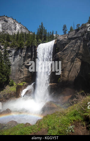 Vernal falls empties into the Merced River below with a double rainbow forming in the mist. Stock Photo
