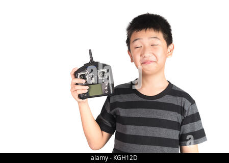 Asian boy holding radio remote control (controlling handset) for helicopter, drone or plane, studio shot isolated on white background. Stock Photo