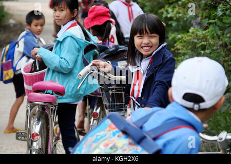 BINH DINH, VIET NAM- NOV 3, 2017: Portrait of Asian pupil after school on bicycle, at Vietnamese countryside, children ride bike to go to school Stock Photo
