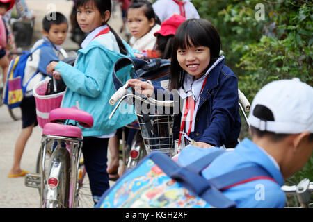 BINH DINH, VIET NAM- NOV 3, 2017: Portrait of Asian pupil after school on bicycle, at Vietnamese countryside, children ride bike to go to school Stock Photo