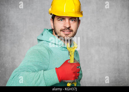smiling worker holding a yellow key in a hand Stock Photo