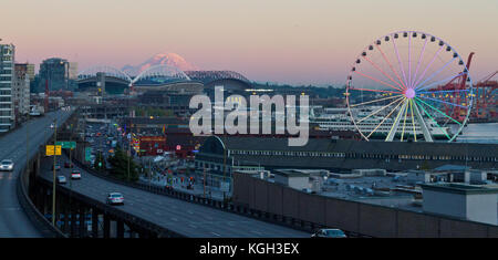 A view of Seattle, Washington shot at dusk which includes Miners Landing, the Great Wheel, Mt. Rainier, and Century Link Field. Stock Photo