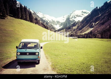 OBERSTDORF, BAVARIA, GERMANY - MAY 10, 2017: Vintage blue and white VW Bully camping car driving on mountain valley road in Trettachtal valley, Allgauer Alps. Stock Photo