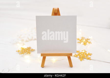Miniature easel with blank card, pine branches and Christmas decorations. Space for text. top view photo mockup Stock Photo