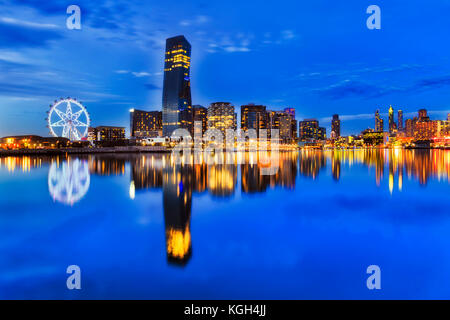 BLue dark sunset at Melbourne Dockalnds area with still Yarra river waters mirroring bright lights of modern ubran high-rise towers and architecture. Stock Photo