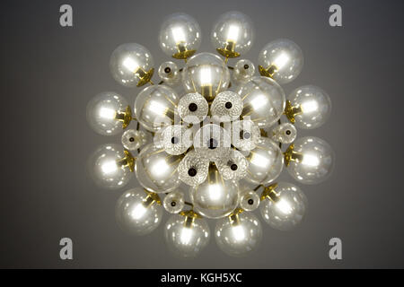 Crystal glass chandelier view from bottom, round shape, round glass bulb covers, lit, energy-efficient light bulbs Stock Photo