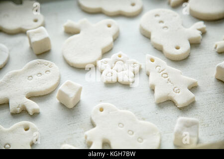 close-up of cut out christmas cookies and pastry cutters in shape of christmas tree, snowman and star, before baking, modeling dough - two parts of fl Stock Photo