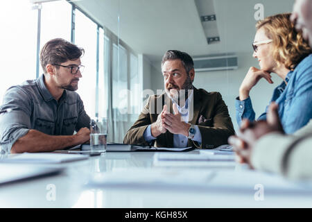 Successful businessman discussing something with his team at conference meeting. businessman explaining project plan to colleagues Stock Photo