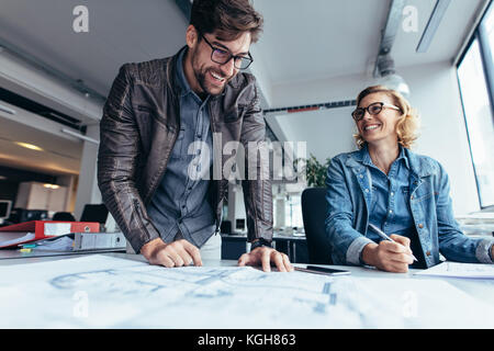 Business partners working together in office. Two architects working on construction plan. Stock Photo