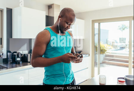 Man listening to music at the kitchen table. Man enjoying music using earphones in kitchen. Stock Photo