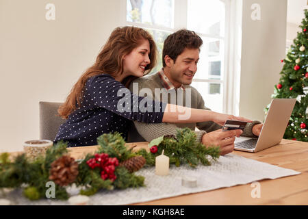 Young family with laptop and credit card buying online christmas and new year gifts. Couple doing online shopping for christmas.