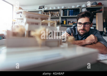 Young architect working on house model.  Male designer at his workdesk thinking about new architectural ideas. Stock Photo