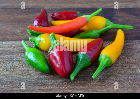 Heap of red, yellow and green hot chili peppers on dark wooden background Stock Photo