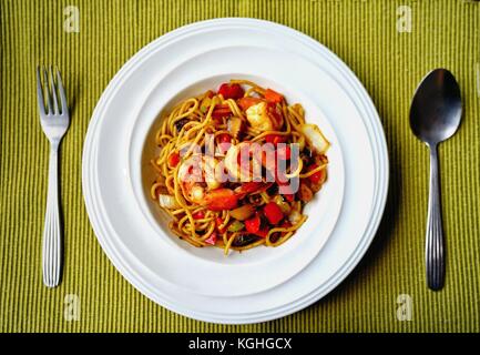 Spaghetti with Thai Spicy Herbal Sauce and prawns on white plate Stock Photo