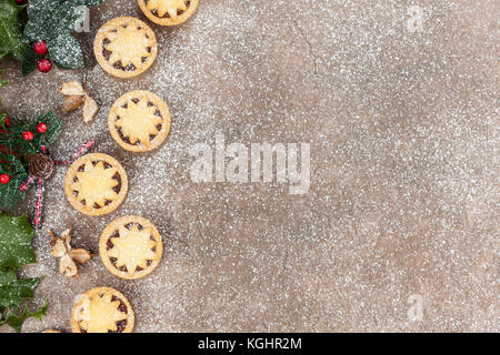 Frosty christmas background with mince pies and holly leaves with red berries Stock Photo