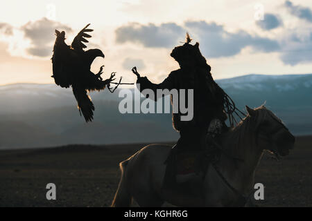Silhouette of the Eagle Hunter traditional clothing, while hunting with a golden eagle in desert mountain of Western Mongolia. Stock Photo