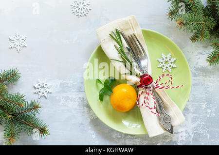 Holiday background. Decor Christmas table on stone or slate background. Green plate, cutlery and decorations. Top view with copy space. Stock Photo