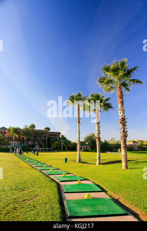 Open air golf driving range in Morocco with mats, piles of balls, palm trees and blue sky. Portrait. No people. Stock Photo