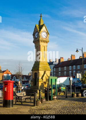 The town clock and a bright red Post Box in the Market Place in Thirsk North Yorkshire UK Stock Photo