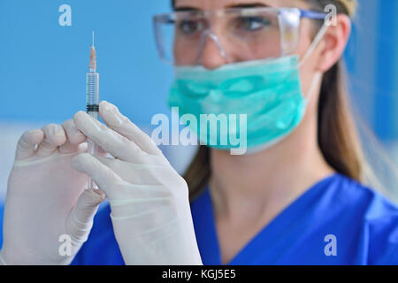 Female dentist holding a dentistry study model and a syringe Stock Photo