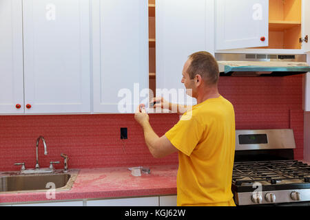Worker installs doors to kitchen cabinet. Installation of doors on kitchen cabinets Stock Photo