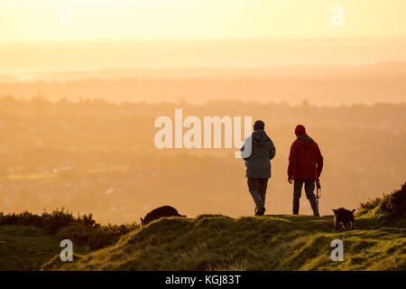 Flintshire, North, UK. 8th Nov, 2017. UK Weather. A cold frosty start for some today after a day's rain yesterday and clearing skies for the rest of the day. Dog walkers dressed for the freezing weather taking a sunrise walk with their dogs walking along the ridgeline of Moel-y-Gaer and Iron Age hillfort near Rhosesmor Credit: DGDImages/Alamy Live News Stock Photo