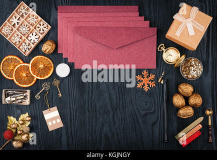 Pack of envelopes, Christmas decorations and postal supplies on a black wooden texture background. Top view with copy space Stock Photo