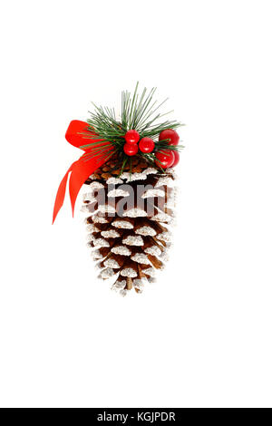 Extra large pine cone decorated with glitter, red holly berries, fir, ribbon and a bell on white background with lots of copy space. Christmas ornamen Stock Photo