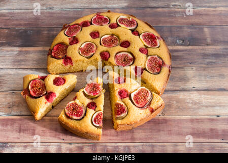 Fig and raspberry cake slices with almonds and a honey glaze on dark brown wood background with copy space. Stock Photo