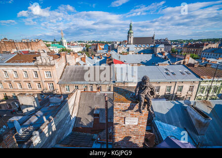 Chimney sweeper statue on the roof of famous restaurant House of Legends on the Old Town of Lviv, Ukraine. Former Bernardine church and monastery on b Stock Photo