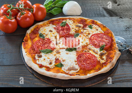 Fresh hot pizza on wood table with ingredients Stock Photo