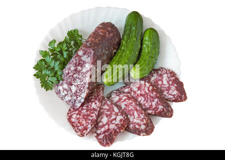 On a white background plate with slices of sausage, cucumber and parsley. Stock Photo
